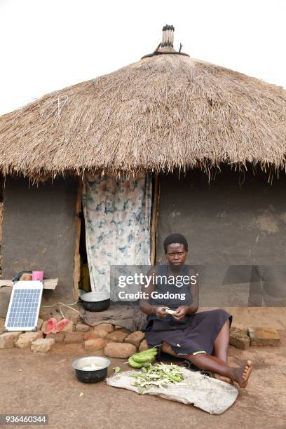 Woman peeling vegetables outside her home. Uganda.