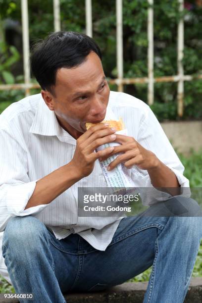 Man eating a sandwich. Ho Chi Minh City. Vietnam.