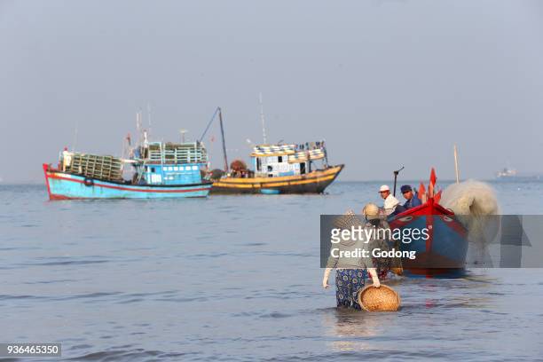 Vung Tau beach. Fishing boats. Women sorting fishing catch. Vietnam.