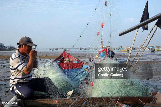 Fisherman preparing a net on the beach. Vung Tau. Vietnam.