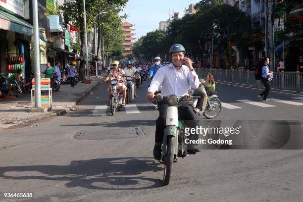 Motor Scooters on Saigon Street. Man using a mobile. Ho Chi Minh City. Vietnam.