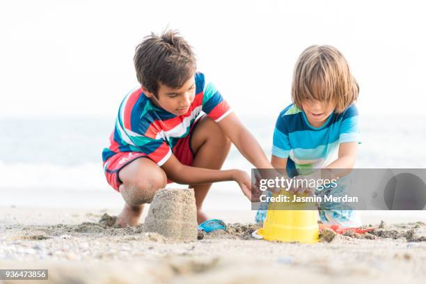 two boys on beach building sandcastle - kind sandburg stock-fotos und bilder