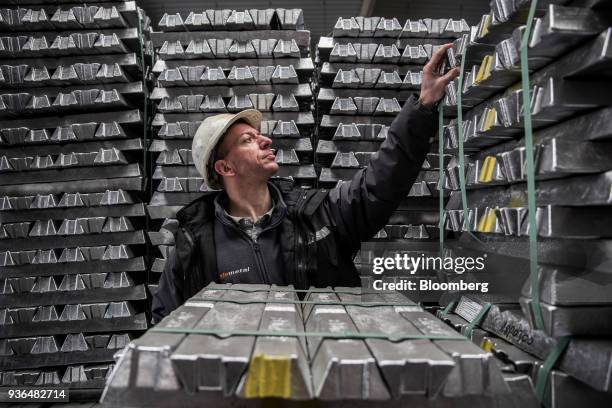 Worker inspects bound aluminum ingots stacked in a warehouse ahead of shipping at the Alumetal Group Hungary Kft. Aluminium processing plant in...