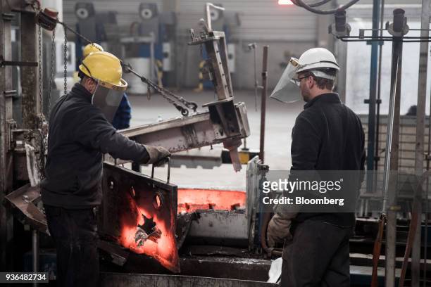 Workers adjust a molten aluminium molding machine at the Alumetal Group Hungary Kft. Aluminium processing plant in Komarom, Hungary on Monday, March...