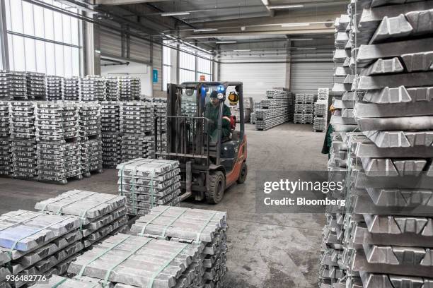 Worker uses a forklift truck to move stacks of bound aluminum ingots in a warehouse ahead of shipping at the Alumetal Group Hungary Kft. Aluminium...