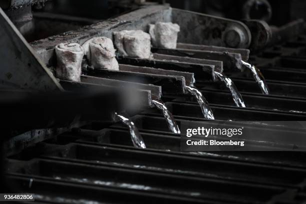 Molten aluminum pours from a molding machine into ingot molds at the Alumetal Group Hungary Kft. Aluminium processing plant in Komarom, Hungary on...