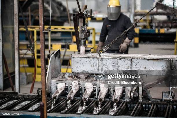 Molten aluminum pours from a molding machine into ingot molds at the Alumetal Group Hungary Kft. Aluminium processing plant in Komarom, Hungary on...