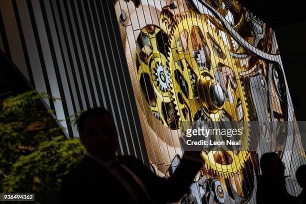 Visitors walk past a giant image of a Blancpain watch complication at the Baselworld watch fair on March 22, 2018 in Basel, Switzerland. The annual...