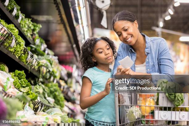 madre e figlia negozio di alimentari insieme usando la lista - spesa foto e immagini stock