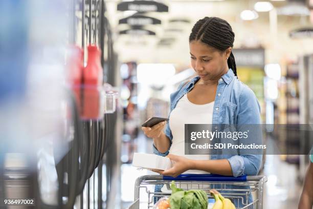 weibliche supermarkt kunde stellt eine schwere entscheidung - frau einkaufswagen ernst stock-fotos und bilder