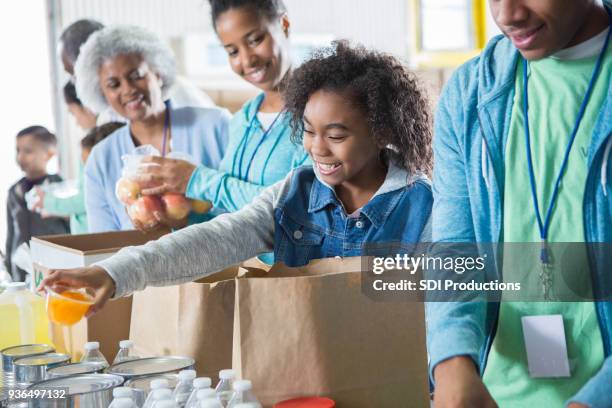 young girl receives donations while volunteering in food bank - father and children volunteering stock pictures, royalty-free photos & images