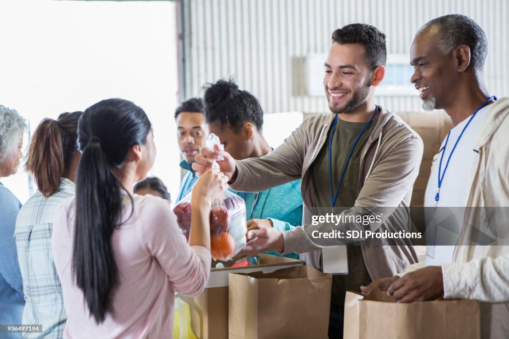 Mulher doa bolsa de fruta para o banco de alimentos