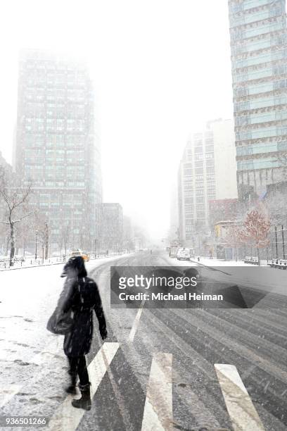 People cross Sixth Avenue while it snows on March 21, 2018 in New York City. Winter Storm Toby is expected to drop over 12 inches of snow across much...