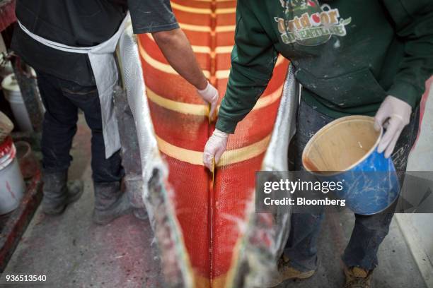 Workers remove excess fiberclass resin from a canoe at the Holy Cow Canoe Co. Production facility in Guelph, Ontario, Canada, on Thursday, March 1,...