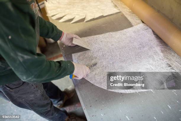 Worker uses a utility knife to cut fibreglass cloth for a canoe shell at the Holy Cow Canoe Co. Production facility in Guelph, Ontario, Canada, on...