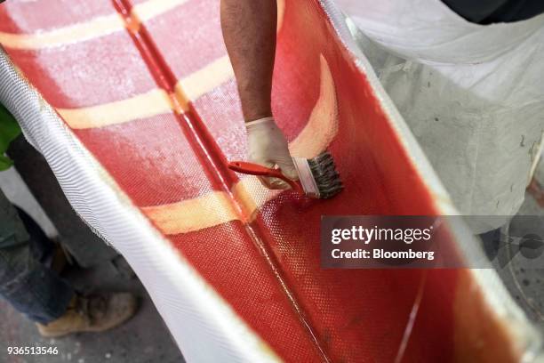 Worker applies fiberclass resin to a canoe at the Holy Cow Canoe Co. Production facility in Guelph, Ontario, Canada, on Thursday, March 1, 2018....