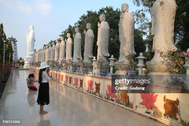 Dai Tong Lam Tu Buddhist Temple. Woman praying in front of Buddha Amitabha statues. Ba Ria. Vietnam.