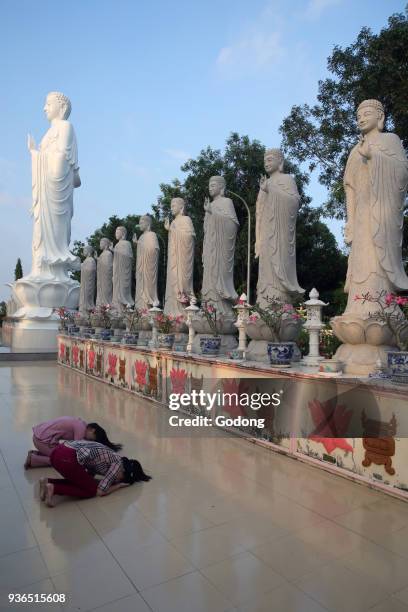 Dai Tong Lam Tu Buddhist Temple. Woman praying in front of Buddha Amitabha statues. Ba Ria. Vietnam.