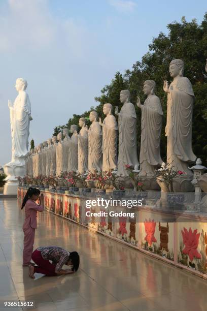 Dai Tong Lam Tu Buddhist Temple. Woman praying in front of Buddha Amitabha statues. Ba Ria. Vietnam.