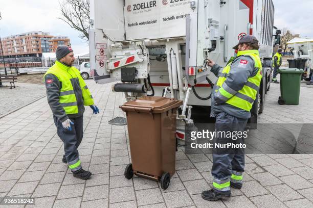 The Suez company grabage collectors emptying waste container into garbage truck are seen in front of new Scania trucks in Gdansk, Poland on 22 March...