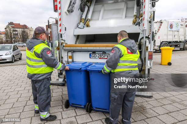 The Suez company grabage collectors emptying waste container into garbage truck are seen in front of new Scania trucks in Gdansk, Poland on 22 March...