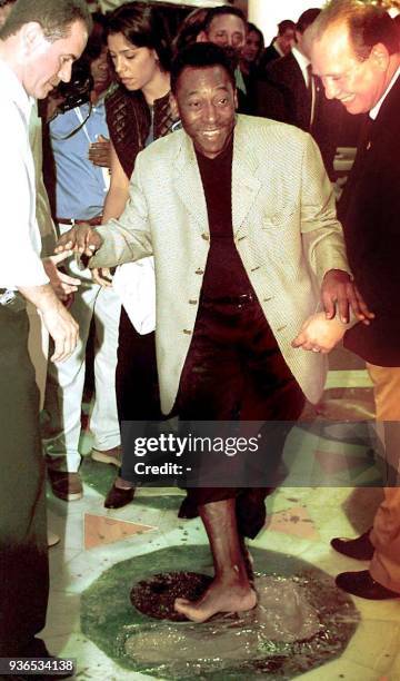 Edson Arantes do Nascimento, known as Pele, steps in fresh cement to leave his mark on the path of fame at the Maracana stage 16 June 2000 in Rio de...