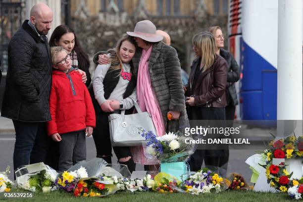 People look at floral tributes, left in Parliament Square in central London on March 22 a year to the day after the Westminster terror attack. -...