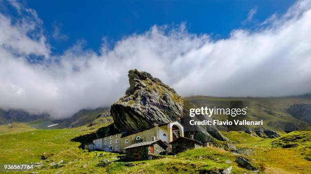 sanctuaire de san besso, construite avec un mur adjacent au rocher monolithique du mont fautenio. il est situé dans la vallée soana, une vallée sur le versant sud du massif du grand paradis. parc national de gran paradiso, piémont, italie - parc national de gran paradiso photos et images de collection