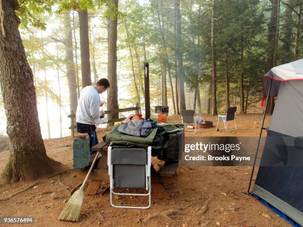 young man arranging supplies at campground. - sturbridge stock pictures, royalty-free photos & images