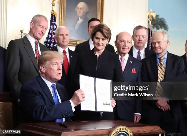 President Donald Trump is flanked by members of the business community as he holds up a signed presidential memorandum aimed at what he calls Chinese...