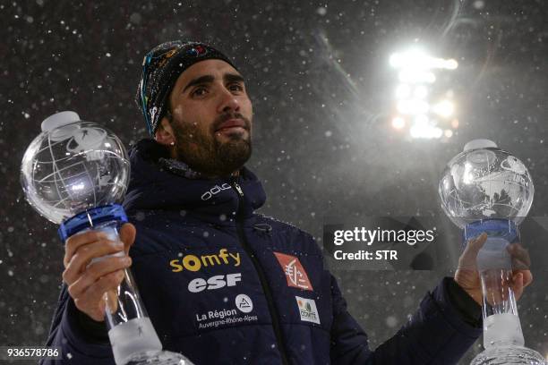 France's Martin Fourcade poses with the small sprint crystal globe and the small globe for the individuals after winning the men's 10 km sprint event...