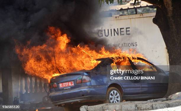 This photo shows a car on fire in a police station in Conakry as anti-riot police clash with Guinean opposition supporters on March 22, 2018. The...