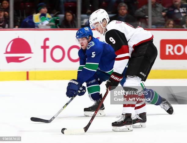 Derrick Pouliot of the Vancouver Canucks checks Clayton Keller of the Arizona Coyotes during their NHL game at Rogers Arena March 7, 2018 in...