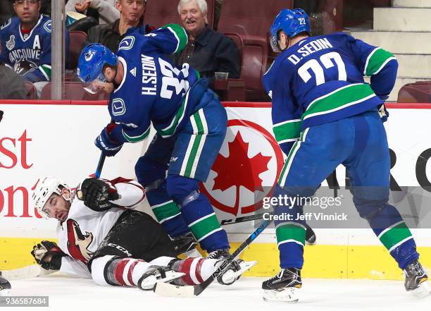 Jordan Martinook of the Arizona Coyotes is checked by Daniel Sedin and Henrik Sedin of the Vancouver Canucks during their NHL game at Rogers Arena...