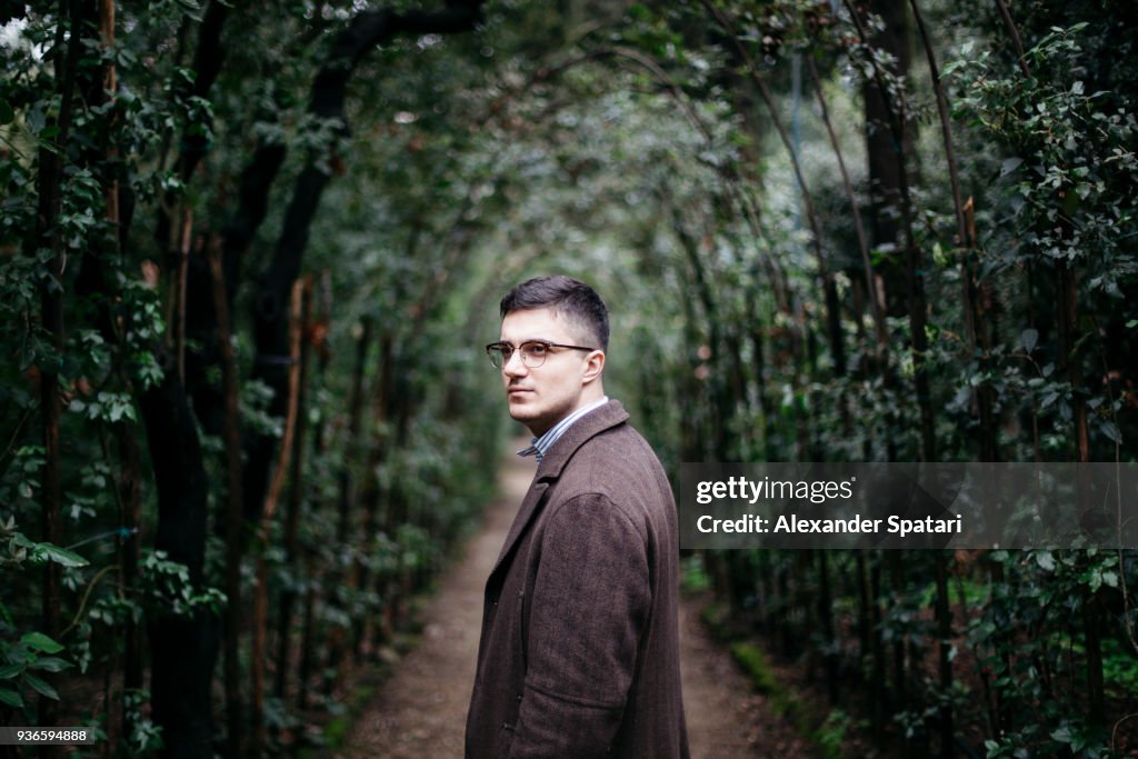Portrait of a young man in eyeglasses in a green maze tunnel