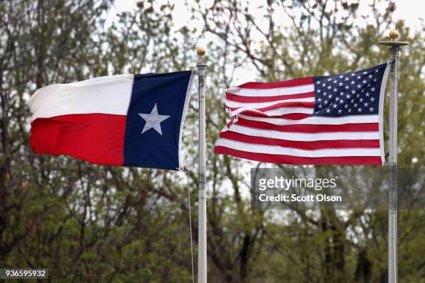 Texas and an American flag fly in front of of St. Augustine's Church, around the corner from the home of Mark Anthony Conditt March 22, 2018 in...