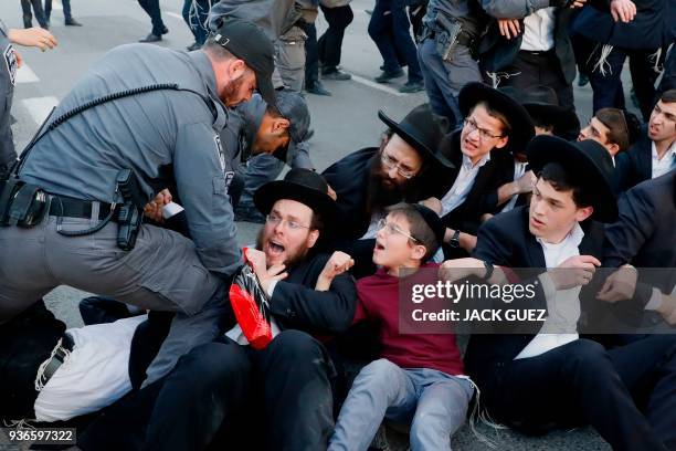 Members of the Israeli security forces try to disperse ultra-Orthodox Jews who are blocking a road during a demonstration against Israeli army...