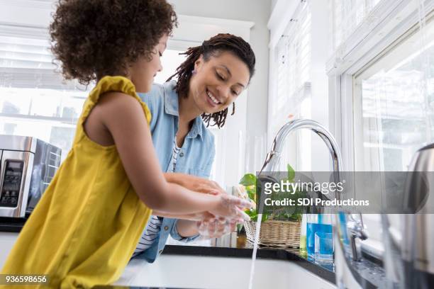mama hilft jungen tochter hände waschen - running water stock-fotos und bilder
