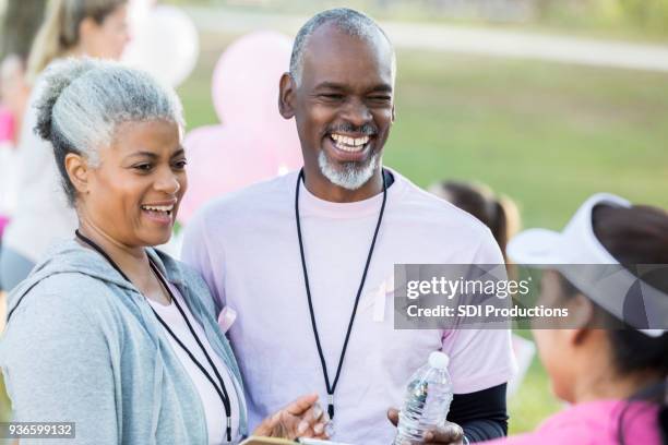 senior couple volunteer during breast cancer awareness event - survival stock pictures, royalty-free photos & images