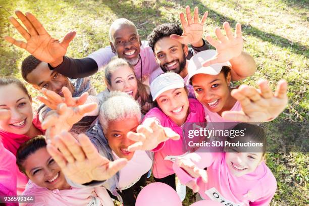 groep mensen bereiken omhoog tijdens een liefdadigheidsevenement - mixed race woman stockfoto's en -beelden