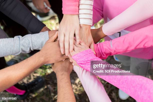 group of people with their hands together in unity - sensibilização-para-o-cancro-da-mama imagens e fotografias de stock