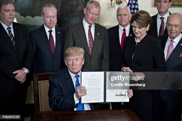 President Donald Trump holds up a signed presidential memorandum targeting China's economic aggression surrounded by business leaders and cabinet...
