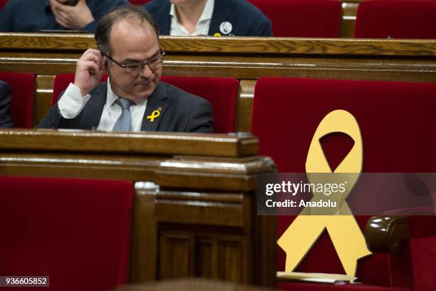 Junts per Catalonia' - JUNTSXCAT member of Catalonia's parliament Jordi Turull looks on as he sits next to yellow ribbon in memory of elected members...