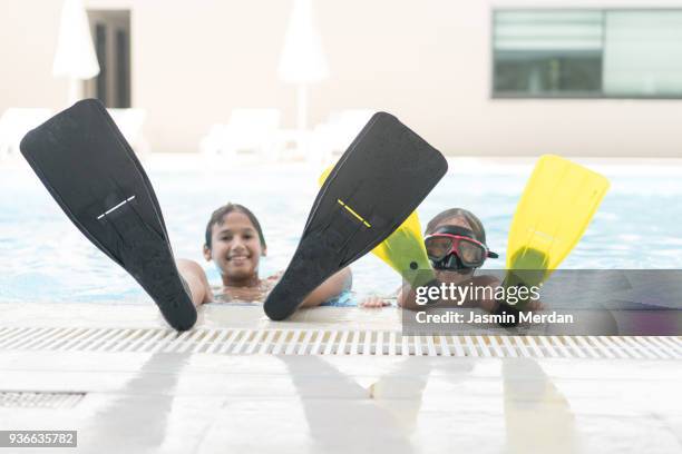 two kids leaning their feet on edge of swimming pool with swimming flippers - ダイビング用のフィン ストックフォトと画像