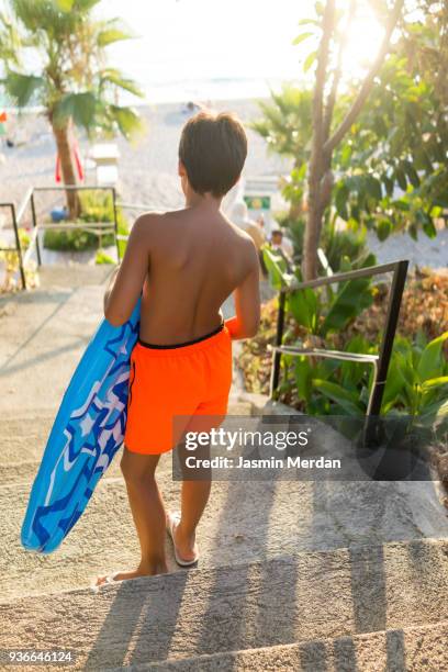 young teenage boy walking with inflatable lounger - teen boy barefoot 個照片及圖片檔