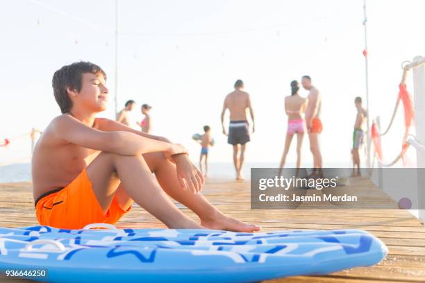 young teenage boy sitting on inflatable lounger - teen boy barefoot 個照片及圖片檔