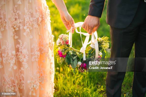 bride and groom holidng floral wreath in their hand - jovanat stock pictures, royalty-free photos & images