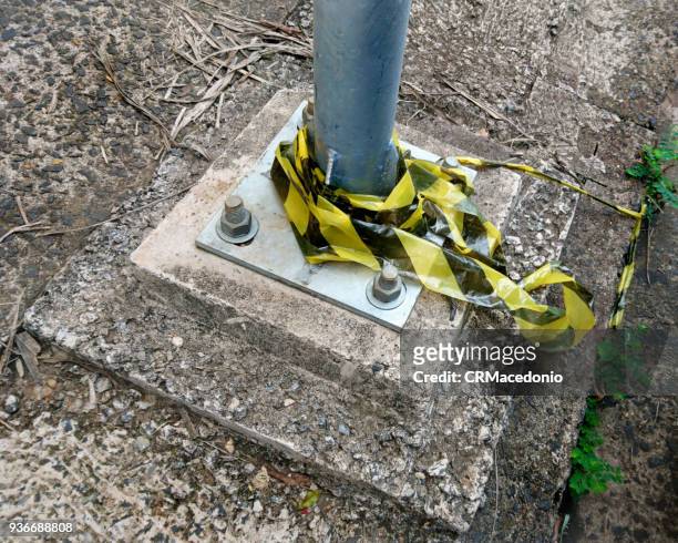 public light pole base, fixed to the floor with screws, and remnants of signaling tape. - crmacedonio stock-fotos und bilder