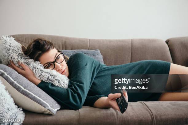 depressed woman changing channels on a tv remote - bores stock pictures, royalty-free photos & images