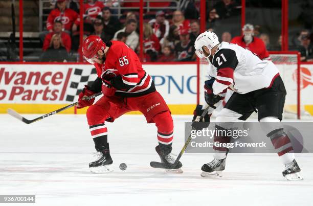 Derek Stepan of the Arizona Coyotes pokes at a puck loose in the skates of Roland McKeown of the Carolina Hurricanes during an NHL game on March 22,...